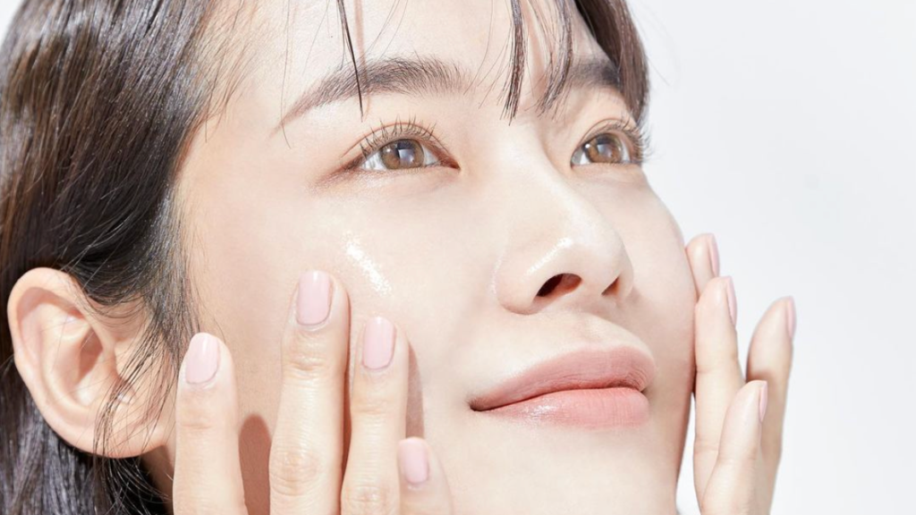 Asian woman applying sunscreen on glowing skin